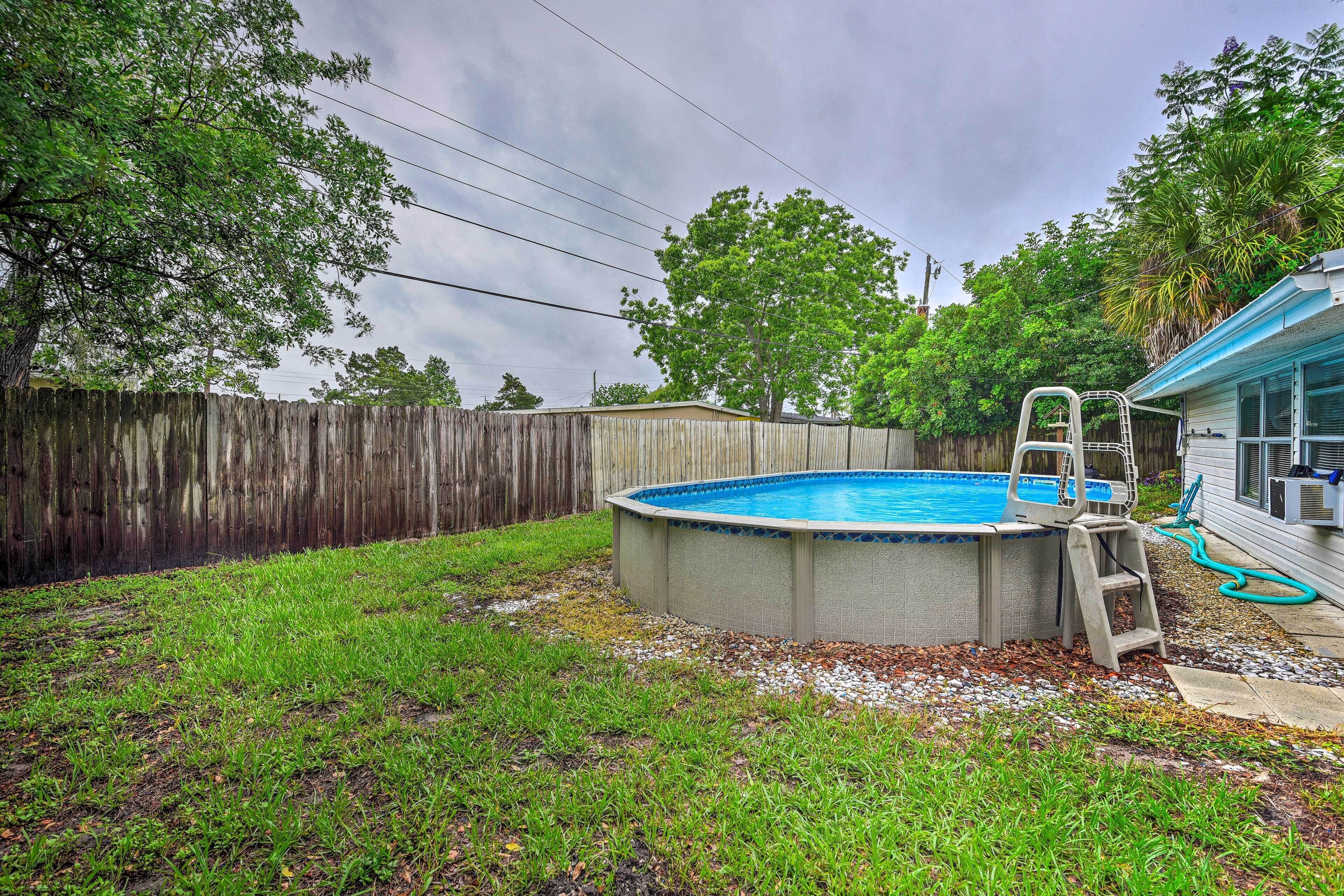A backyard with a swimming pool, a wooden fence, and a ladder leading to the pool.