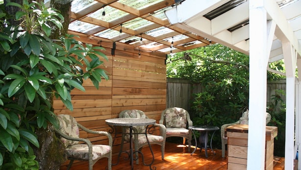 Eine Holzterrasse mit Glasdach, umgeben von üppiger Vegetation.