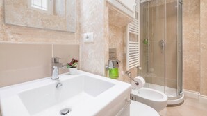 Une salle de bain moderne avec une grande baignoire blanche, des toilettes séparées et une douche à parois de verre.