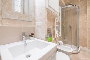 Un bagno moderno con una grande vasca da bagno bianca, un WC separato e una cabina doccia in vetro.