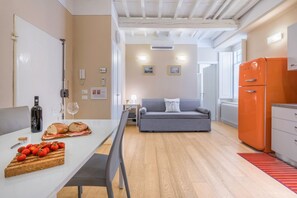 Una cucina moderna con zona pranzo, un divano grigio e un frigorifero arancione.