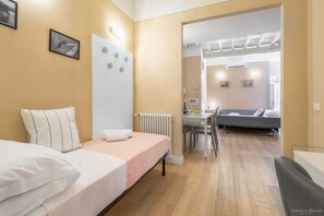 Una camera da letto con un letto, un comodino, un termosifone e vista su un'area pranzo con tavolo e sedie.