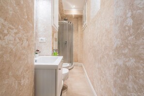 Un baño estrecho con bañera, inodoro y cabina de ducha.