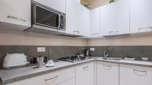 A modern kitchen with white cabinets, a microwave, a gas stove, a toaster, and a sink. - Spacious apartment on the first floor, recently renovated, modernly furnished, consisting of two double bedrooms, two complete bathrooms, sofa bed for 2 guests and single bed in the living room. It can comfortably accommodate up to 7 people. WLAN, air con (Firenze)