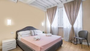 A bedroom with a bed, a nightstand, a chair, and a window with curtains. - Spacious apartment on the first floor, recently renovated, modernly furnished, consisting of two double bedrooms, two complete bathrooms, sofa bed for 2 guests and single bed in the living room. It can comfortably accommodate up to 7 people. WLAN, air con (Firenze)