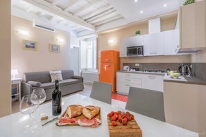 Una cocina moderna con armarios blancos, un microondas y un refrigerador rojo.