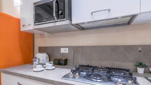 Une cuisine équipée d’une cuisinière à gaz, d’un four à micro-ondes et d’un grille-pain. Elle comprend des placards et un plan de travail.