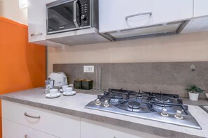Una cucina con piano cottura a gas, forno a microonde e tostapane. Sono presenti armadietti e un piano di lavoro.