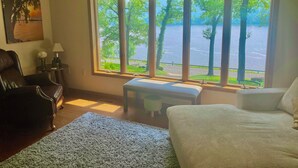A room with a large window, a leather chair, a bench, and a bed.