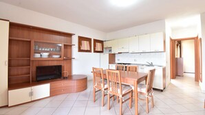Een moderne keuken met witte kastjes, een eettafel met stoelen en een ingebouwde televisie.