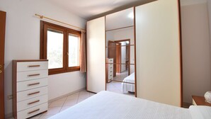 Een slaapkamer met een bed, een dressoir, een kast en een raam.
