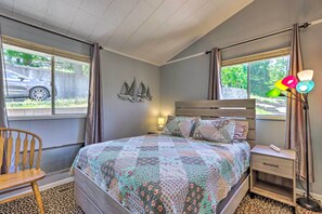 Ein Schlafzimmer mit einem Bett, einem Nachttisch, einem Stuhl und einem Fenster mit Vorhängen.