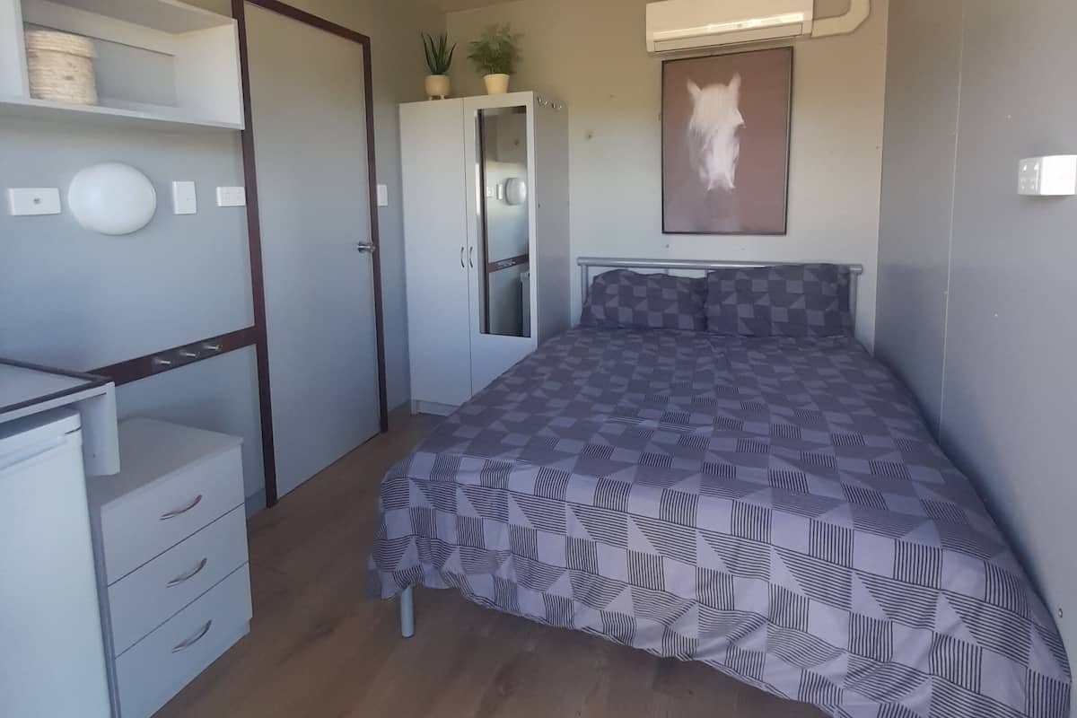Un dormitorio con cama, armario, escritorio y espejo.