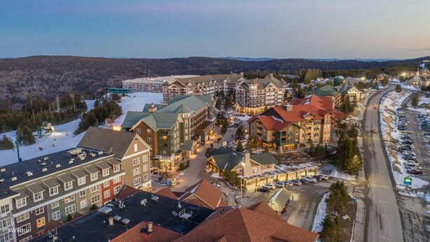 A ski resort with multiple buildings, including a hotel with a red roof and a large sign. - Mountain Lodge - Ski In/Out - 2 Queen Bedrooms + 2 Bunk Beds - Closest To Lifts (Snowshoe)