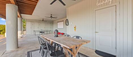 A covered outdoor area with a dining table, chairs, ceiling fans, and a door labeled 'laundry'.