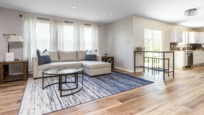 A modern living room with a sofa, coffee table, and a dining area with a table and chairs. - Westfield Gem! 7 Mins to Grand Park + Movie Room! (Westfield)