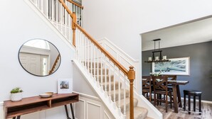 A staircase with white railings and wooden balusters, leading to a dining area with a table and chairs. - Westfield Gem! 7 Mins to Grand Park + Movie Room! (Westfield)