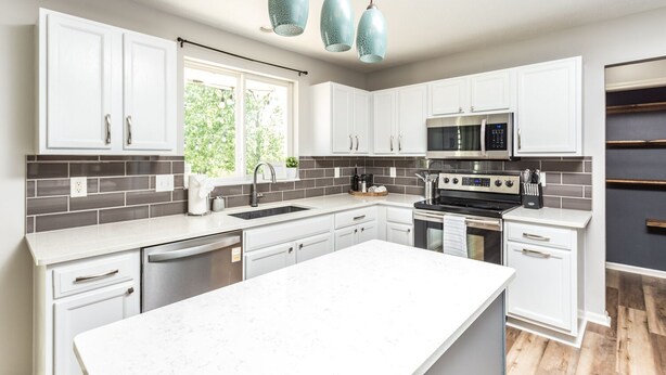 A modern kitchen with white cabinetry, a large island, stainless steel appliances, and blue pendant lights. - Westfield Gem! 7 Mins to Grand Park + Movie Room! (Westfield)