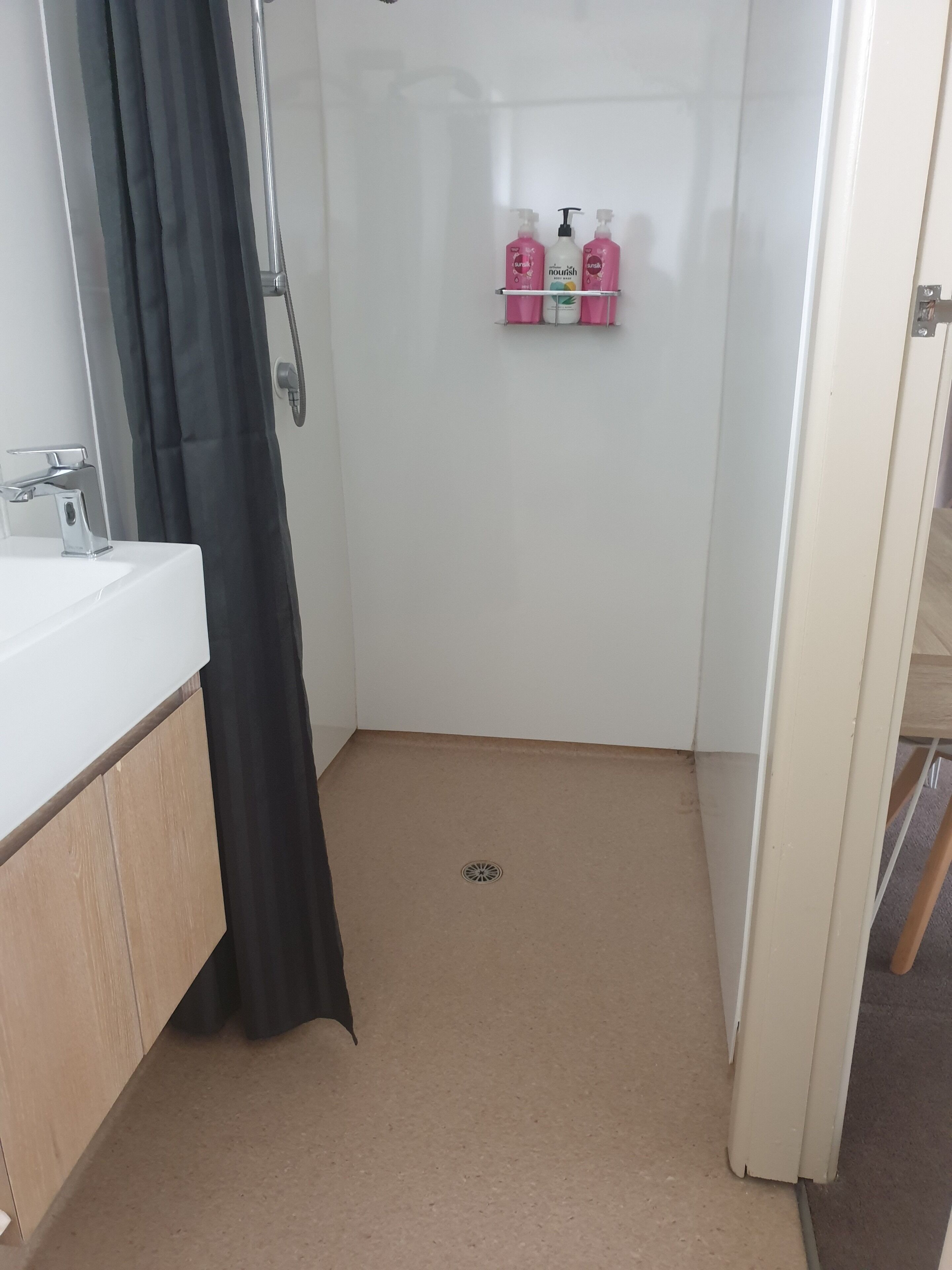 Un bagno con doccia, lavandino e ripiano con articoli da toilette.