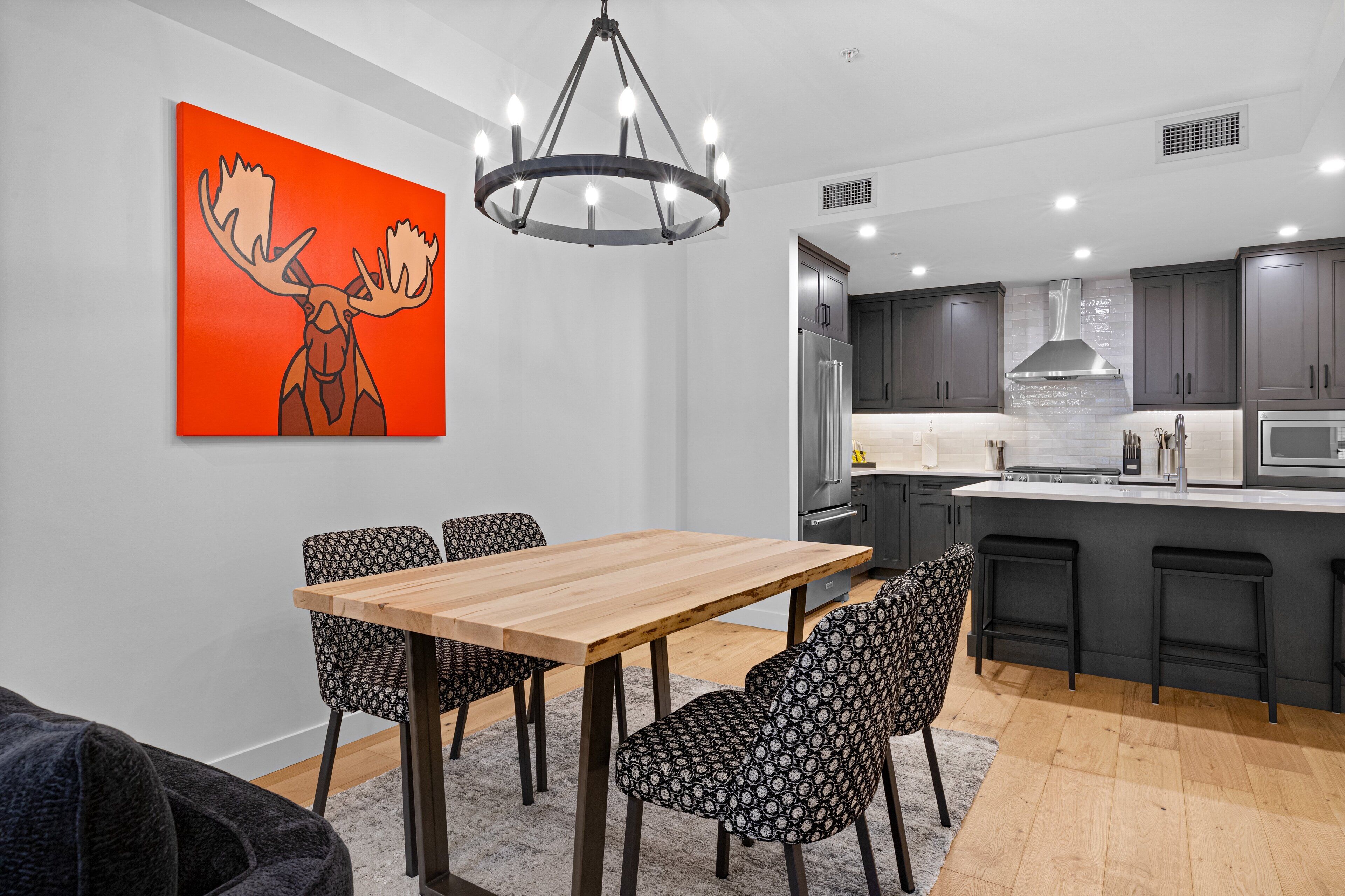 A modern kitchen with dark cabinets, a stainless steel refrigerator, and a central island with bar stools.