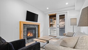 Una sala de estar moderna con chimenea, televisor de pantalla plana, sofá y mesa de comedor.