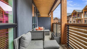 A balcony with wicker furniture and a view of other buildings.