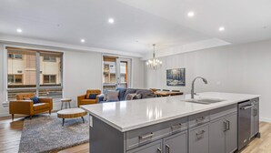 A modern kitchen with a large island, grey cabinetry, and a central island sink.
