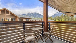 Een balkon met houten meubels en uitzicht op bergen.