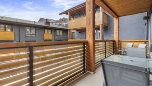 Un balcon avec des balustrades en bois, une table en verre et une chaise.