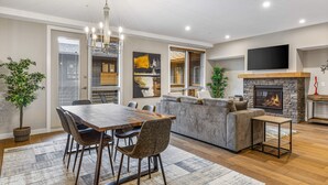 Un salon moderne avec une cheminée, un coin repas avec une table et des chaises en bois, et un grand canapé.