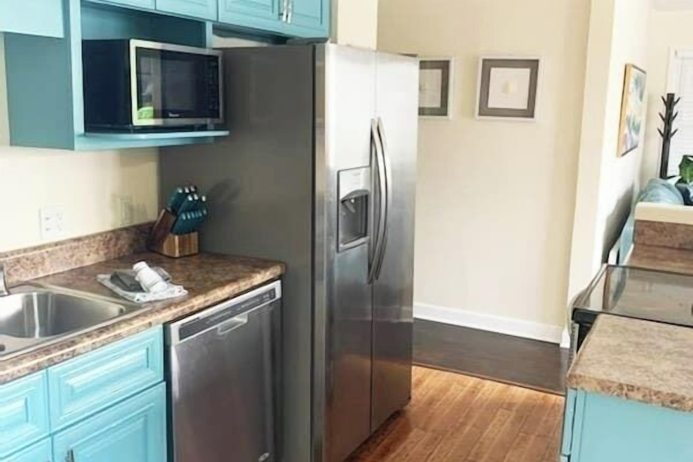 Una cocina con refrigerador de acero inoxidable, microondas y lavavajillas.