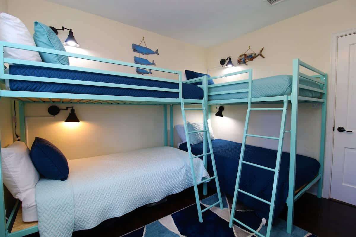 A bunk bed room with a ladder, a desk, and a door.
