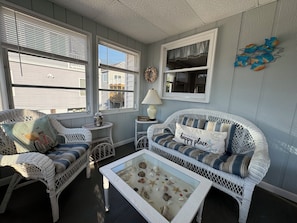 Relax in this inviting living room with a nautical theme, featuring a comfortable sofa and a coffee table showcasing seashells and starfish.