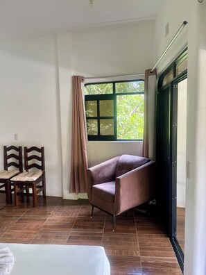 A room with a bed, a chair, a table, and a window with curtains. - Villa del Mar (San Pedro Pochutla)