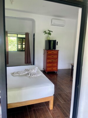 A bedroom with a bed, a wooden dresser, an air conditioning unit, and a window with curtains. - Villa del Mar (San Pedro Pochutla)