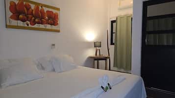 Una habitación de hotel con una cama bien hecha, un cuadro en la pared, una lámpara en una mesita de noche y una ventana con cortinas.