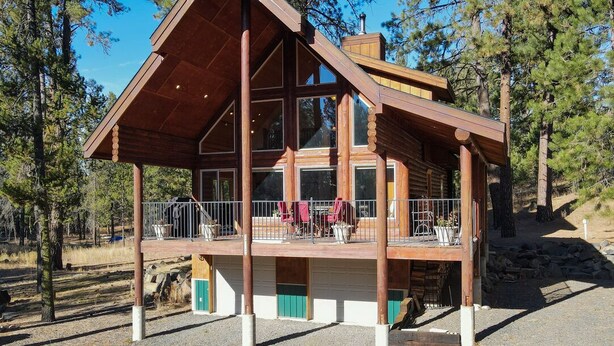 A log cabin with a covered porch, large windows, and a garage. - Log Cabin Getaway: WIFI, GameRoom, Firepit, pets OK! (Cascade)