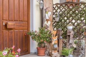 Una puerta de madera, una planta en maceta, un enrejado de madera y un adorno rústico en la pared.
