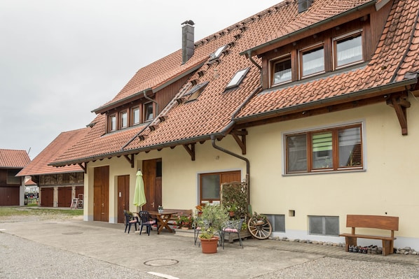 Il s’agit d’un bâtiment traditionnel, doté d’un toit en tuiles, de poutres en bois et d’un espace extérieur abrité avec des chaises et une table, aménagé pour accueillir les clients.