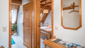 Une pièce avec une porte en bois, un lit, un luminaire suspendu et un miroir au mur.