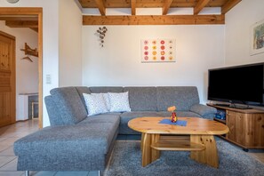 Un salon moderne avec un canapé gris, une table basse en bois et un téléviseur à écran plat.