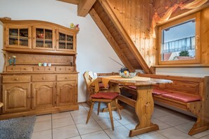 Un coin repas en bois comprenant un banc, une table et un buffet aux portes vitrées.