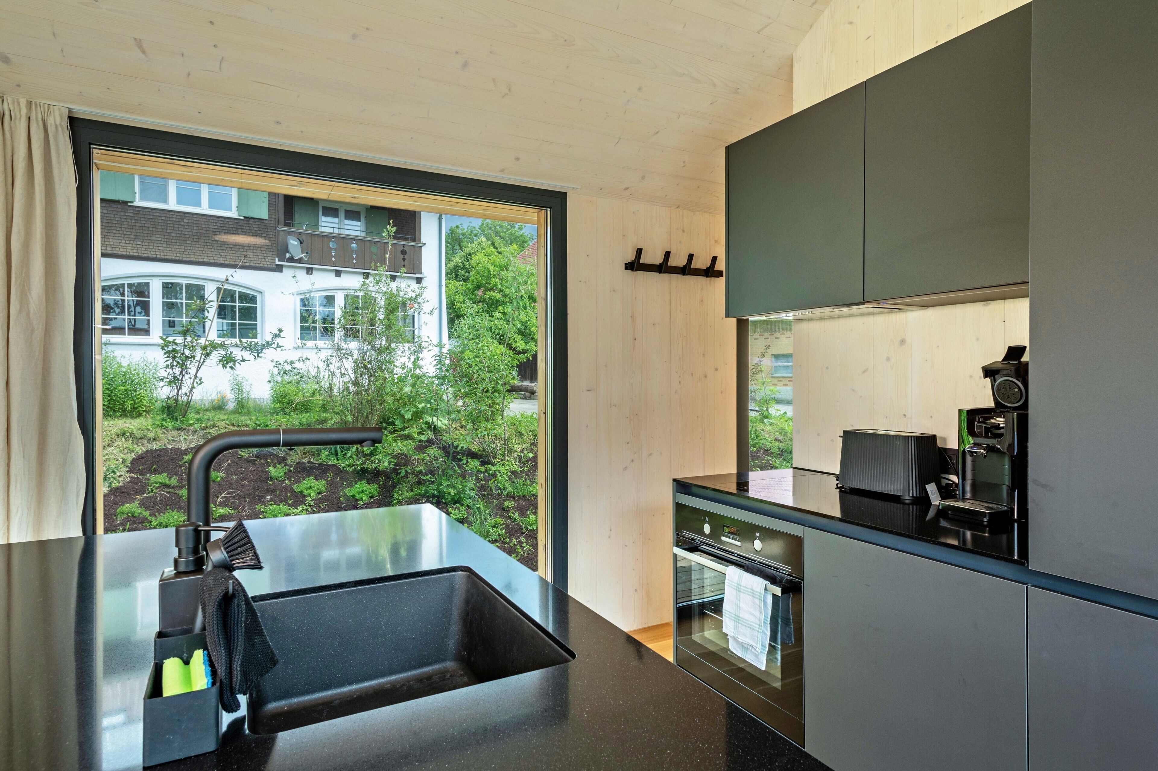A modern kitchen with a large window, a sink, and a coffee machine.