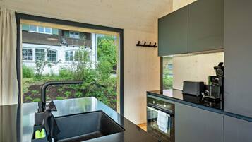 A modern kitchen with a large window, a sink, and a coffee machine.
