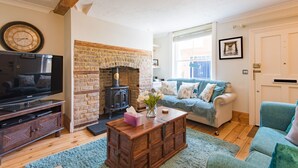 A cozy living room with a brick fireplace, a television, and a comfortable seating area.