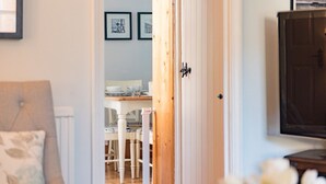 A room with a wooden door, a white radiator, a white chair, and a table with a white tablecloth.