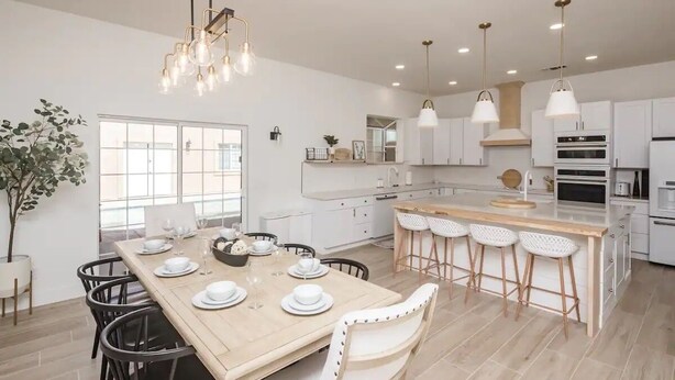 A modern kitchen with white cabinetry, a central island with bar stools, and pendant lighting. - Heated Pool ~ Sleeps 20 ~ HUGE Family Resort Oasis (Lake Havasu City)
