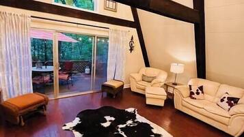 Un salón amplio con un gran ventanal, un tapiz de cuero de vaca, un sofá y un banco.
