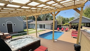 A covered outdoor deck with a hot tub, lounge chairs, and a swimming pool. - Play @ The Hideaway - hot tub, sauna, gymnasium (Three Oaks)