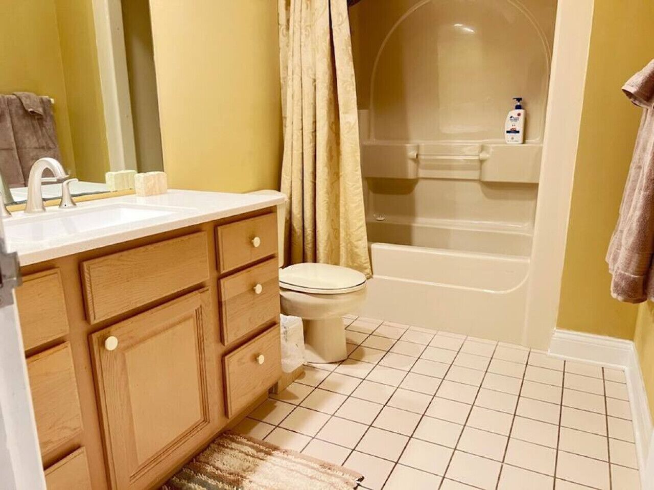 A bathroom with a wooden vanity, a white sink, a toilet, and a bathtub.